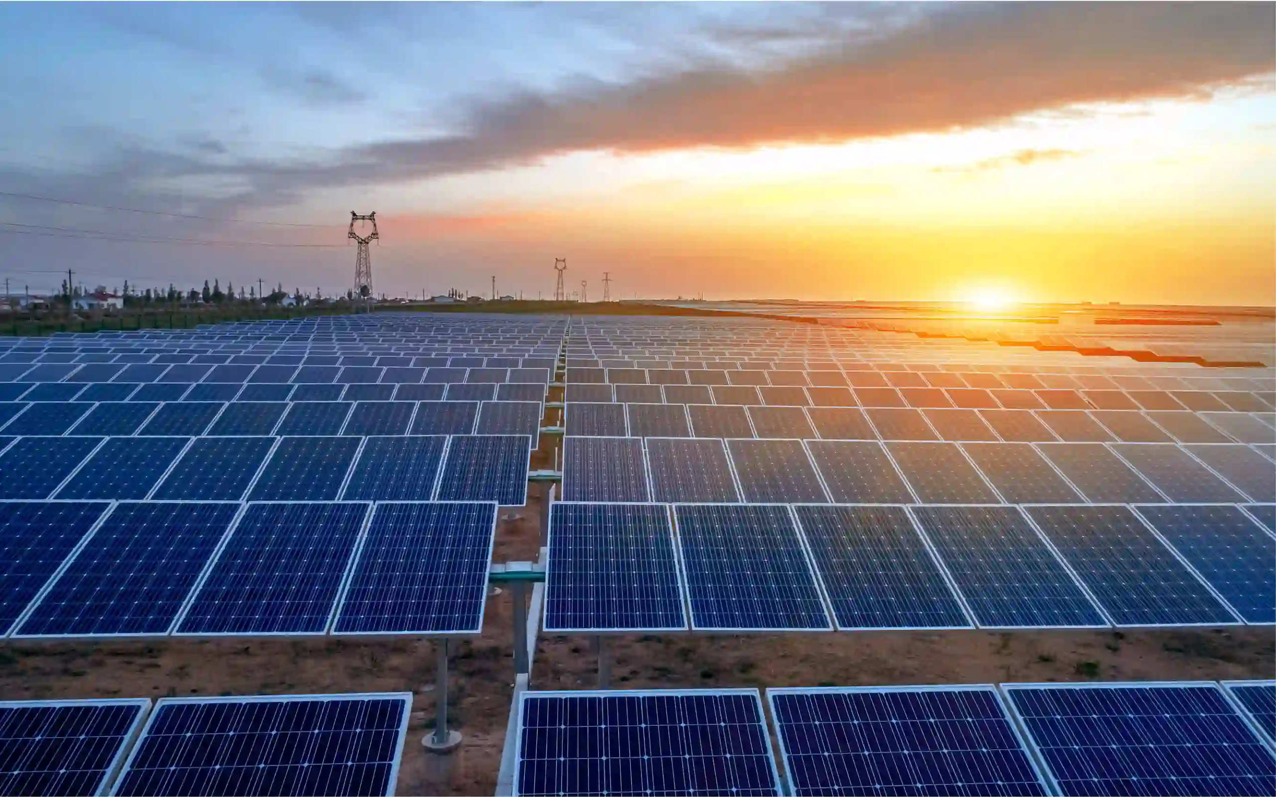 a field of solar panels with the sun in the background