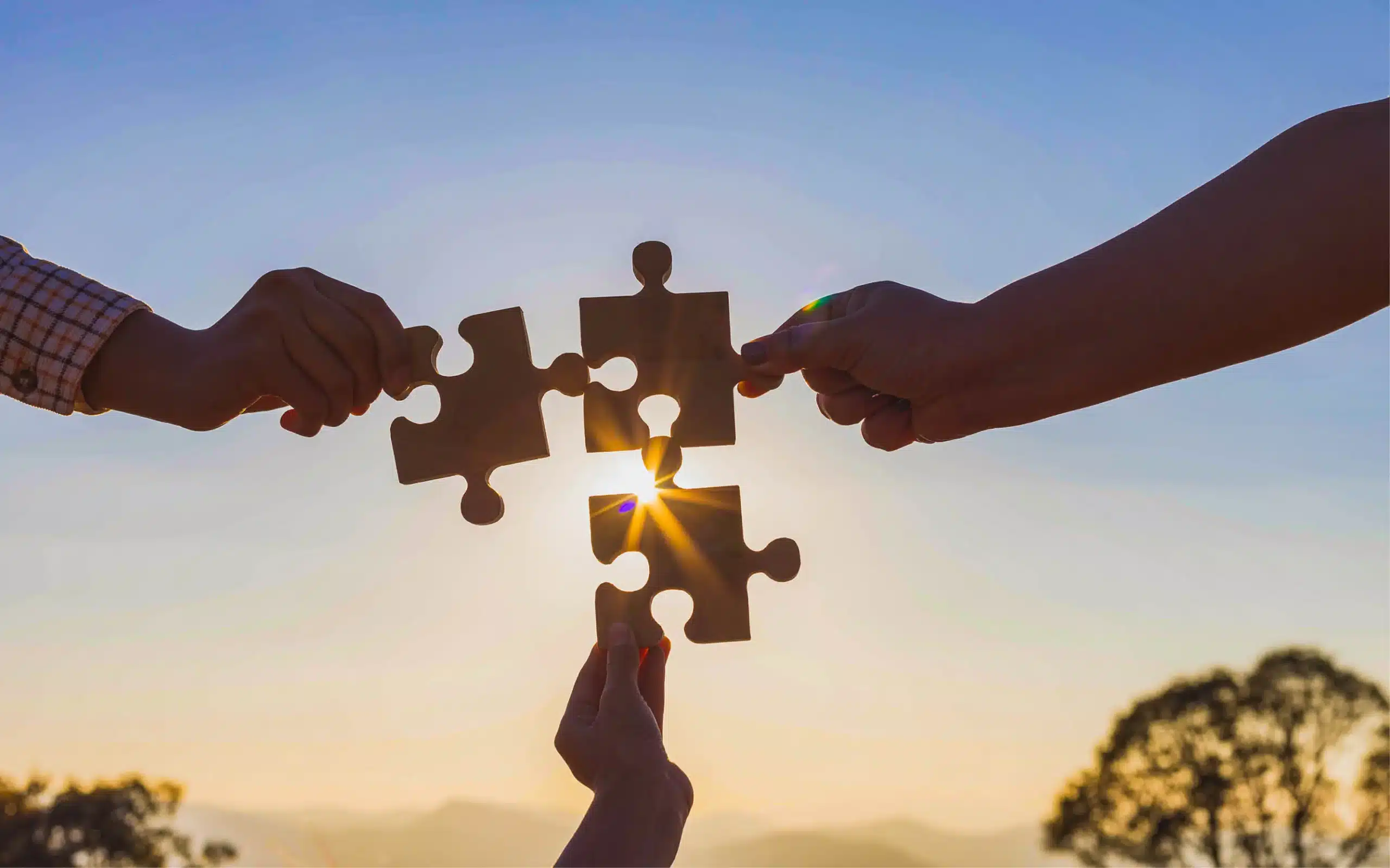 hands holding puzzle pieces coming together to connect them