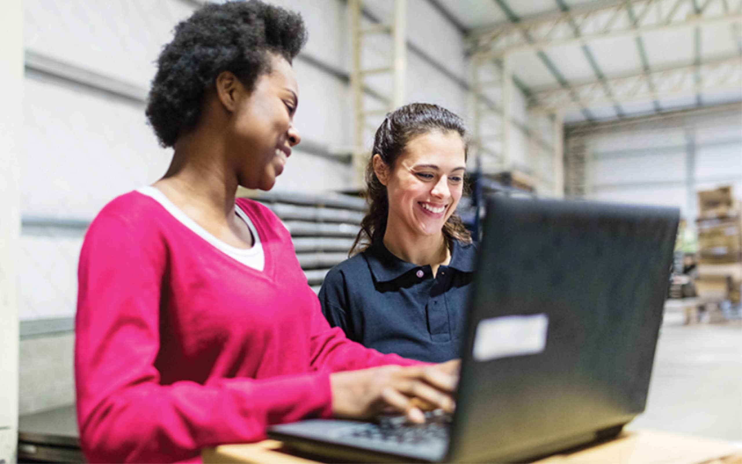 diverse students in a warehouse working together on a laptop